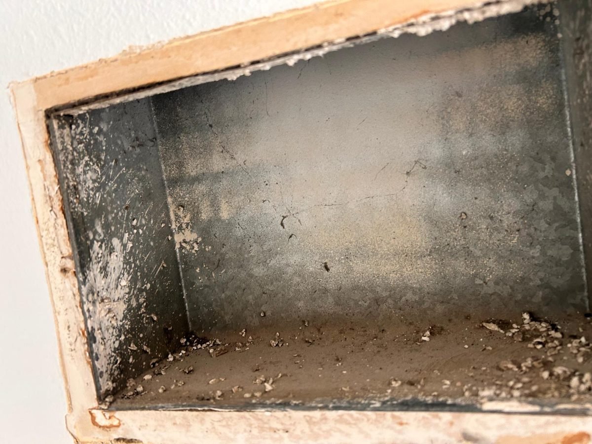 Wall register opening coated with dust and debris